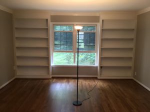 empty room with window in between 2 white bookshelf accent walls