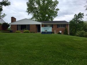 small brick house with premier painting banner in lawn