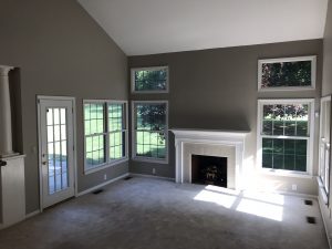 open room with dark grey walls white ceiling, large windows surrounding central fireplace